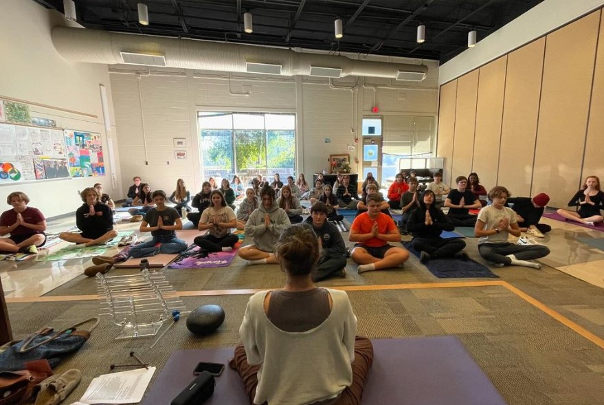Students from the Humanities Specialty Center sitting on the floor doing yoga.
